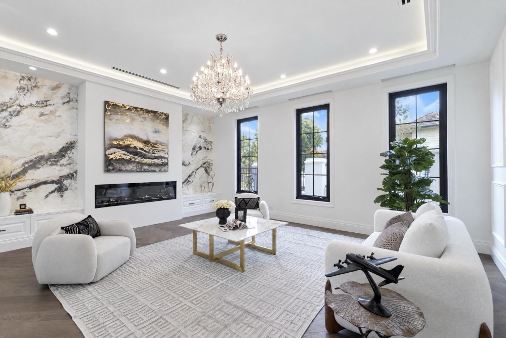 A white living room with marble feature walls and a long built in gas fireplace, the fire unlit